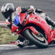 Honda CBR600RR 2027 in HRC-kleuren op het circuit, onder hellingshoek in een bocht