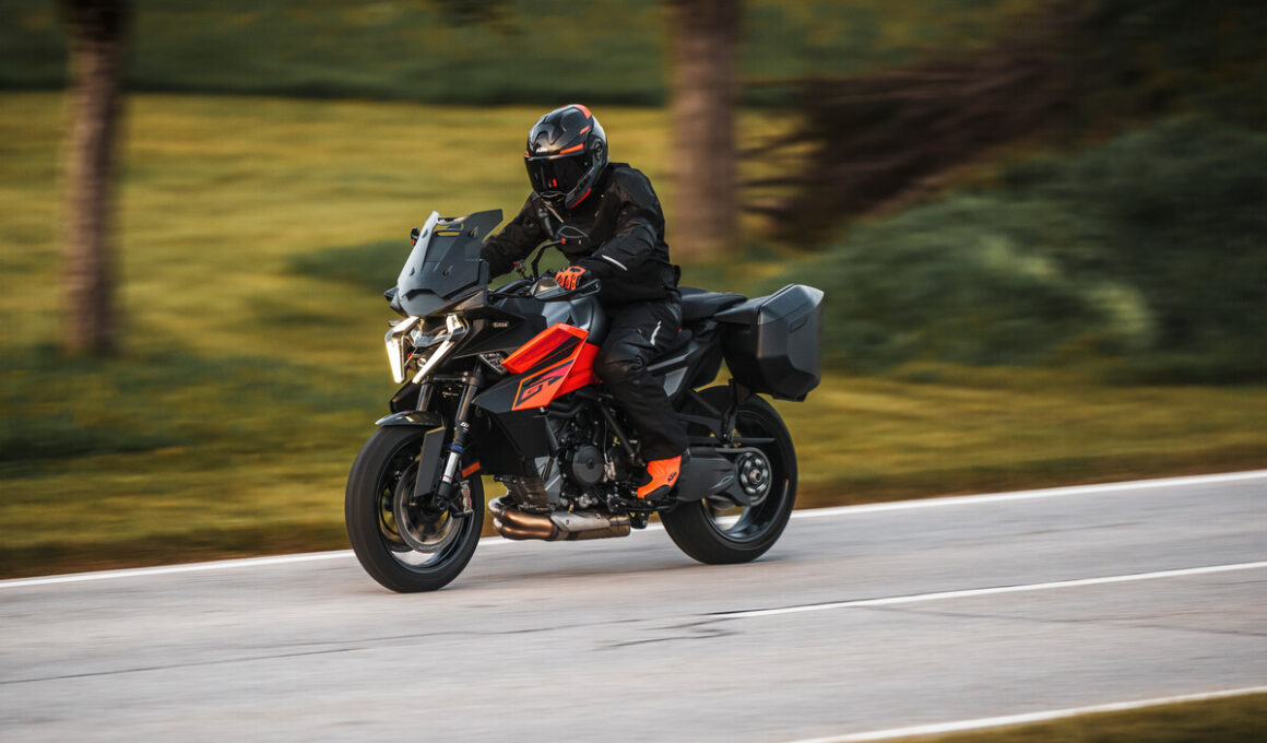KTM 1390 Super Duke GT in bocht op openbare weg met zijkoffers, officiële persfoto uit 2024